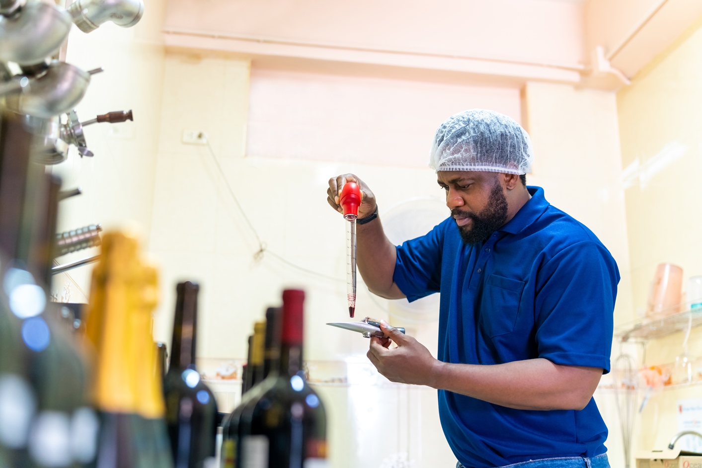 Vigneron en train de travailler et d’examiner du vin rouge dans la salle de contrôle qualité. Fabrication de vins, alcool et processus de vinification.