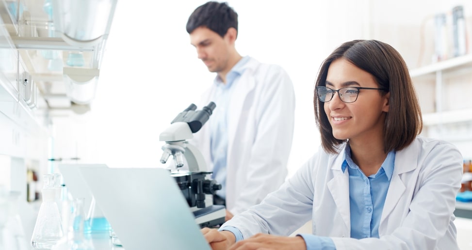Une femme utilise un système LIMS et un cahier de laboratoire électronique dans le laboratoire.