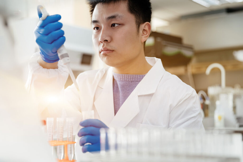 Asian man with pipette in lab