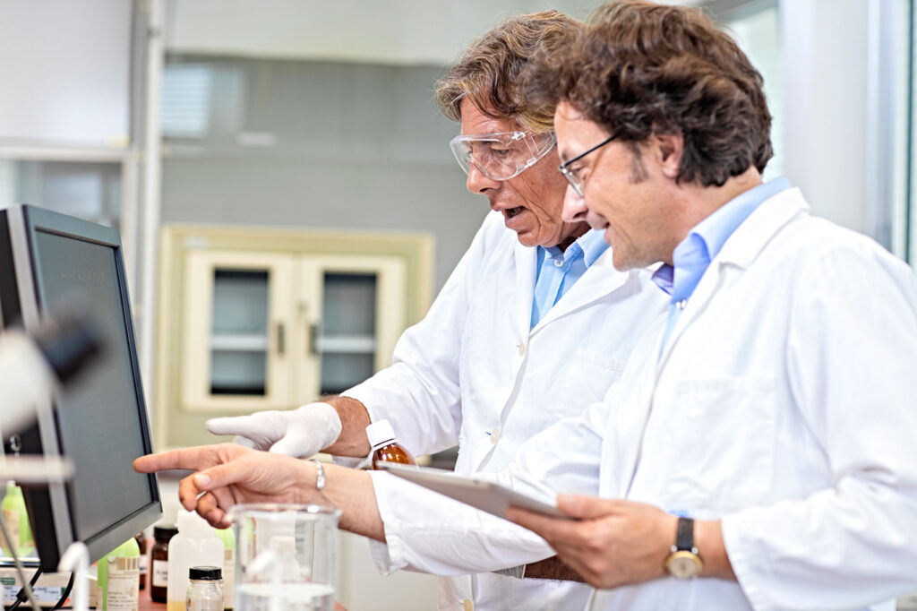 two men at computer screen in lab