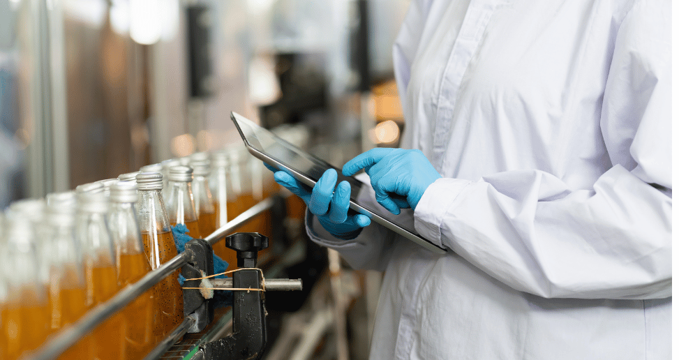 Hands of worker working with digital tablet check product on the conveyor belt in the beverage factory.