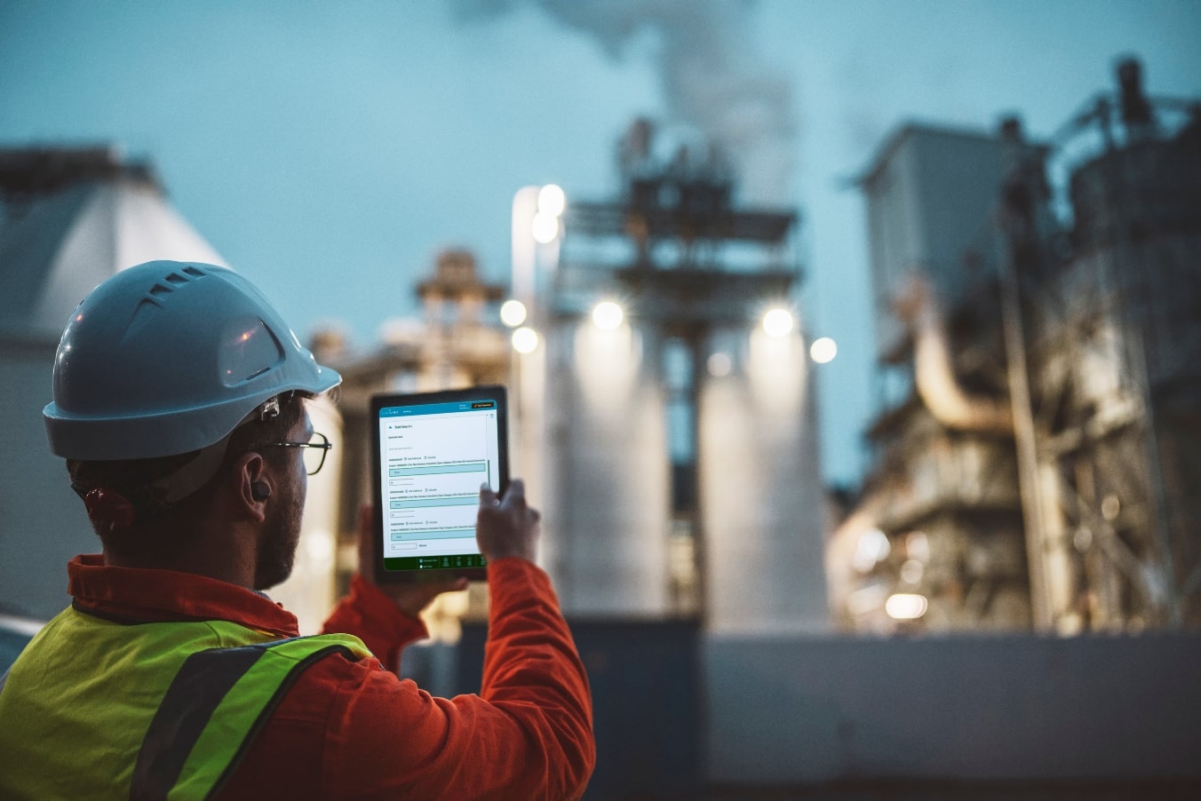 A man with a hard hat reviews STARLIMS LES Laboratory Execution Systems outside a chemical plant