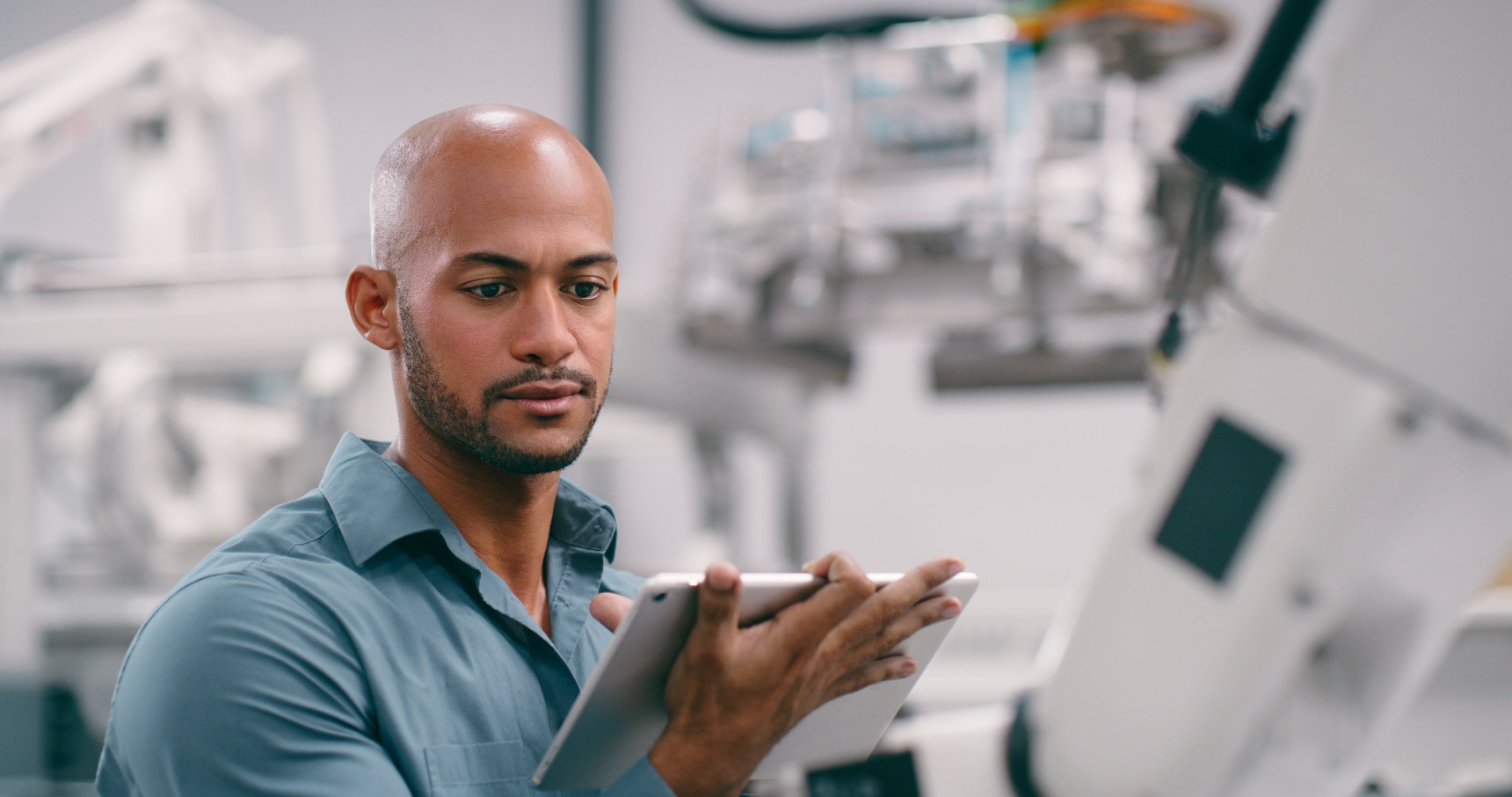 Man in factory works on tablet.