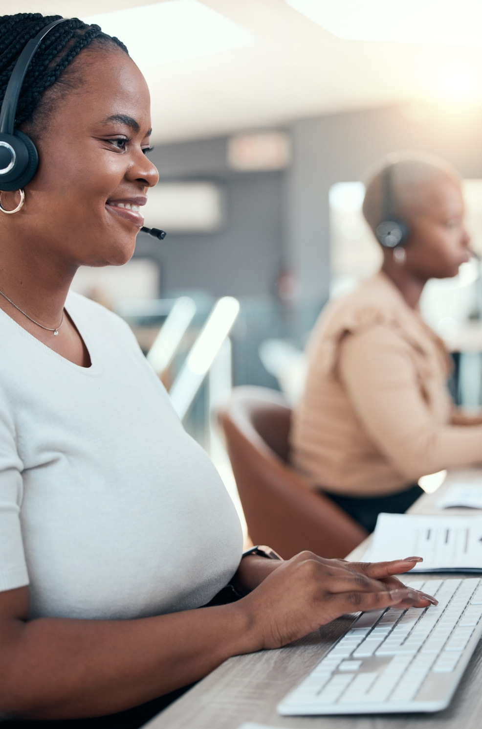 A woman wearing a headset in a call center smiles.