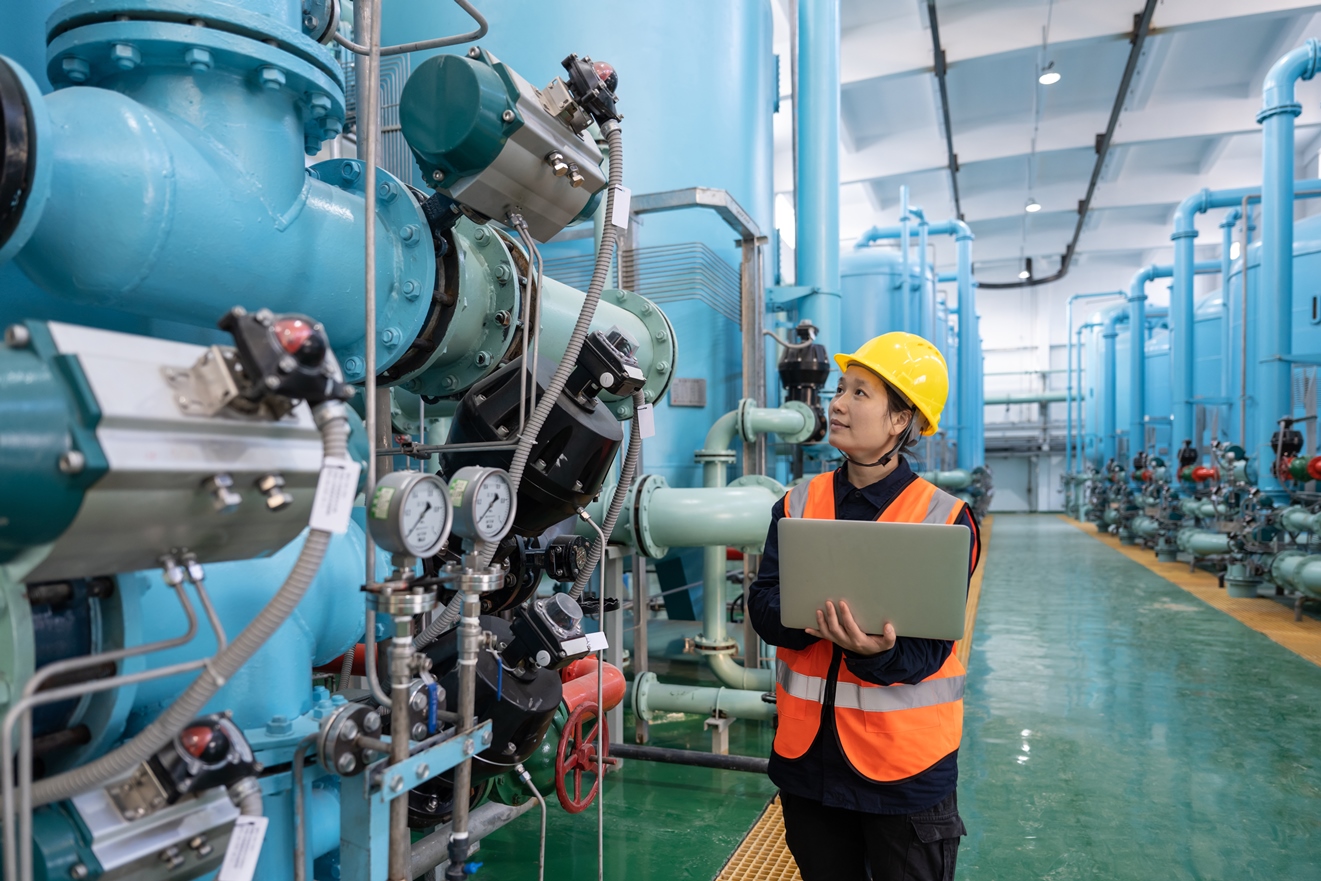 A female technician works in a chemical plant using chemical LIMS, ELN, LES, and SDMS systems on a laptop computer.