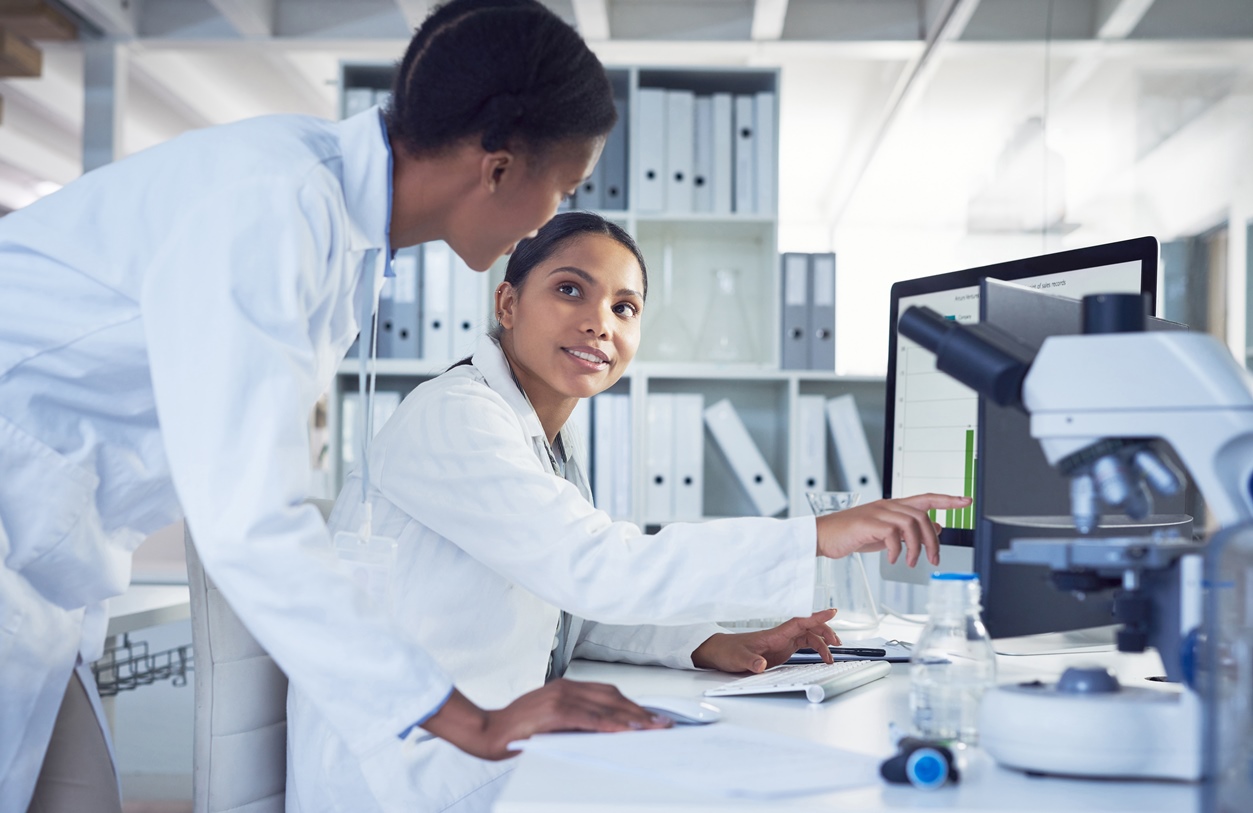Two scientists working together to use a laboratory information management system - LIMS - on a computer in a lab
