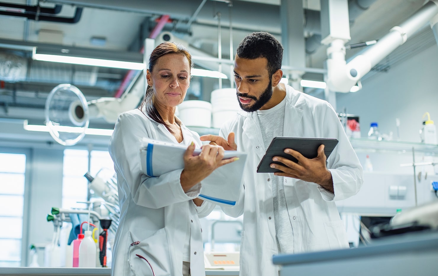 Laboratory workers working together, the man holding a tablet with public health LIMS, ELN, LES, & SDMS solution.