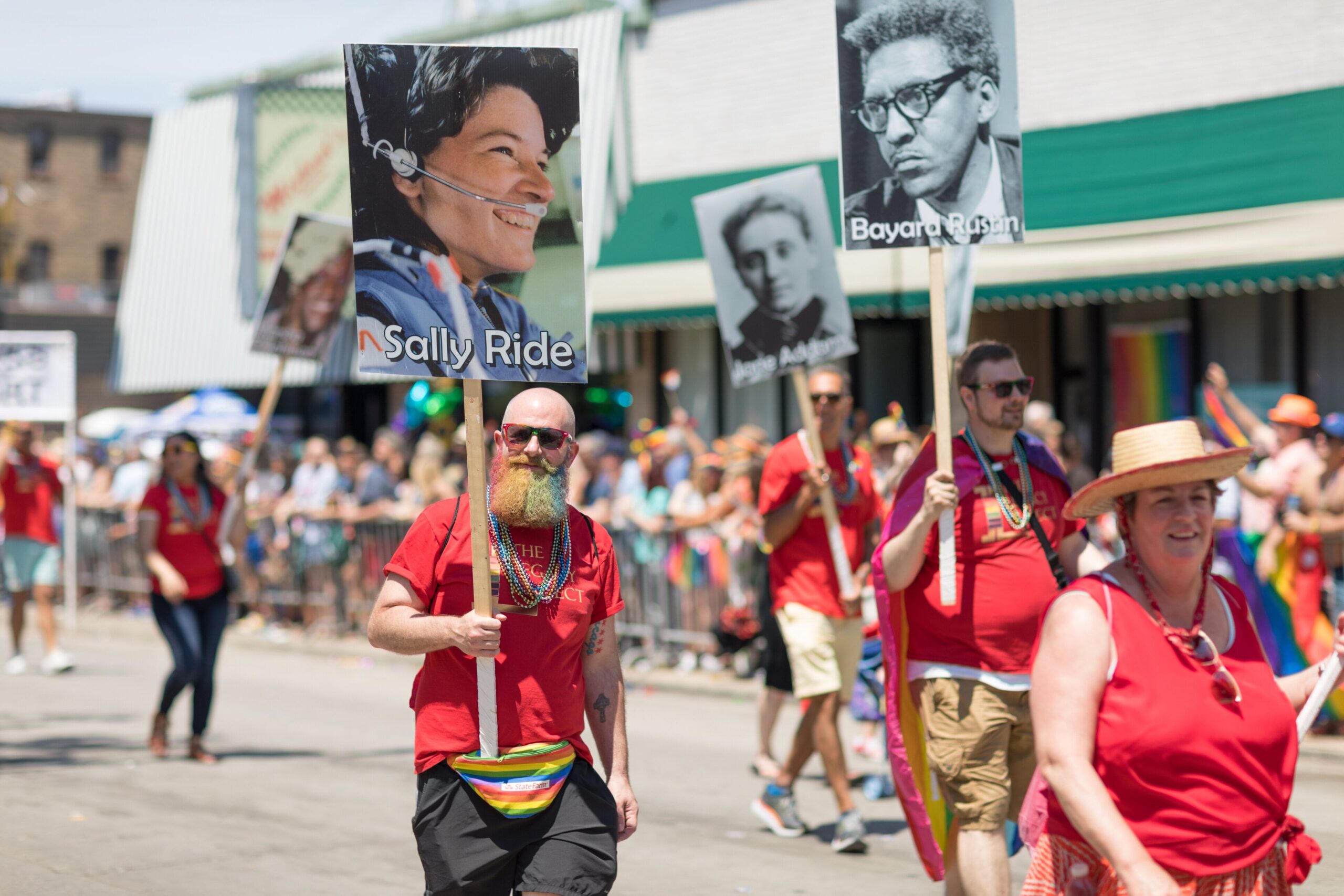 Chicago, Illinois, USA - June 24, 2018 People carrying signs with photos of important gay, lesbian historical characters, Sally Ride, Bayard Rustin, during the LGBTQ Pride Parade in Chicago