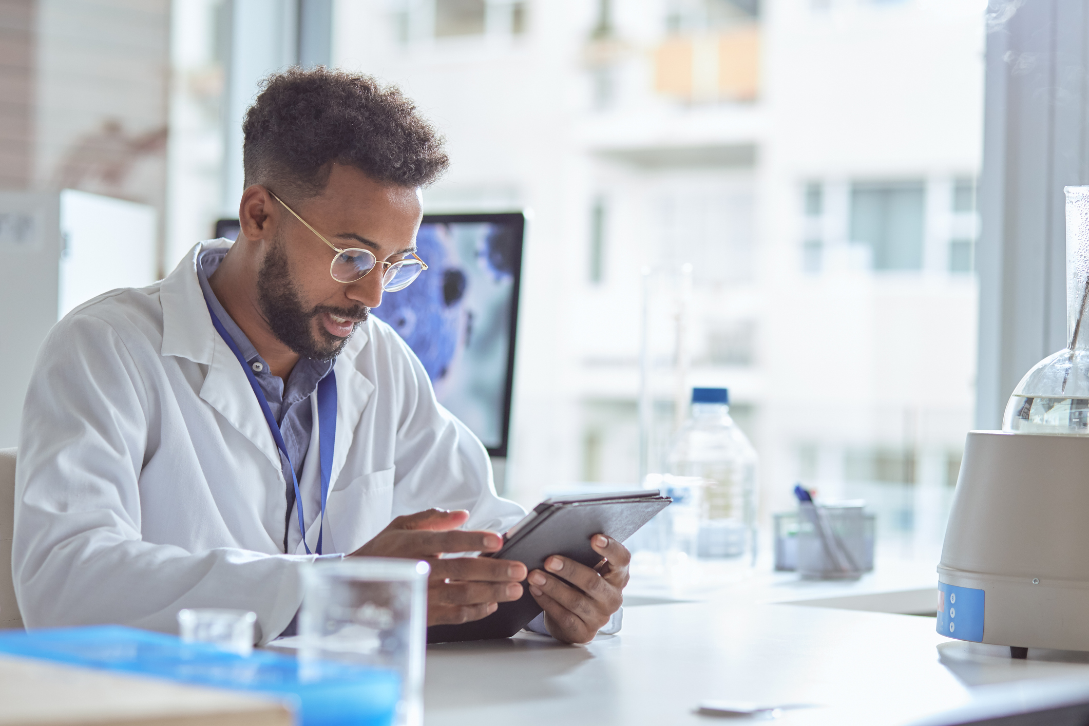 Young man uses the best laboratory information management system in the lab on his tablet.