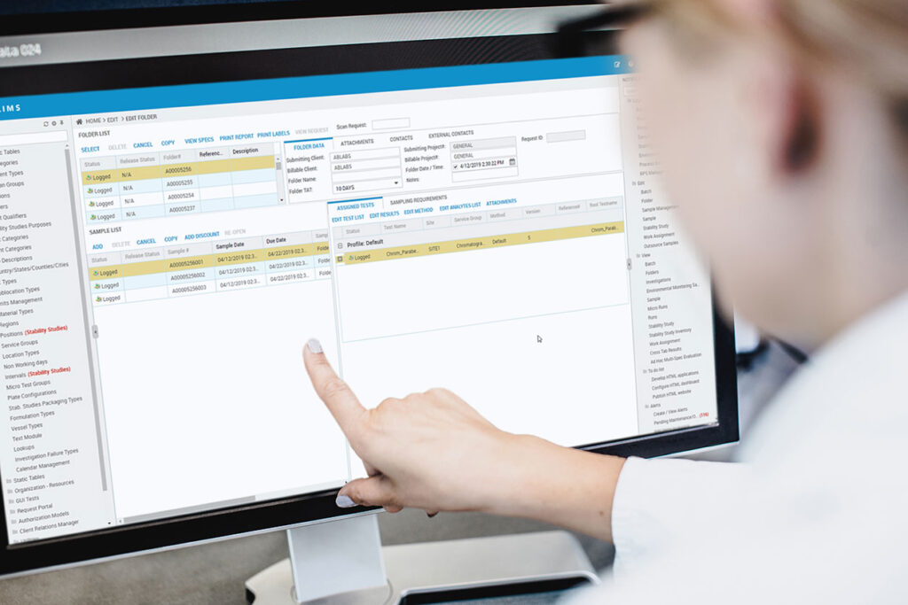 Person pointing at laboratory information management system (LIMS) on a computer screen.
